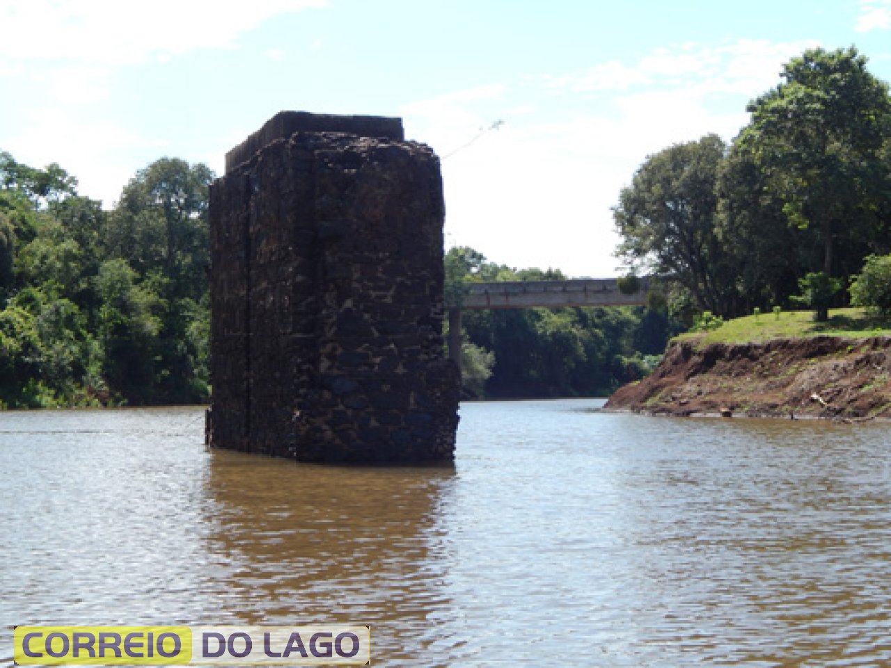 Um dos pilares da Ponte Queimada, vista de perto. Verdadeira Muralha de pedra. Ao fundo a atual ponte de concreto que liga o município de Santa Helena e Diamante do Oeste PR. Foto março/2015.